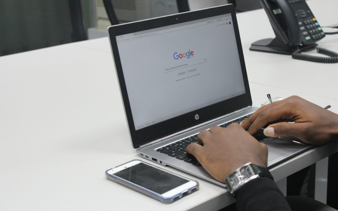 A person searching on their laptop with its screen displaying the Google homepage.